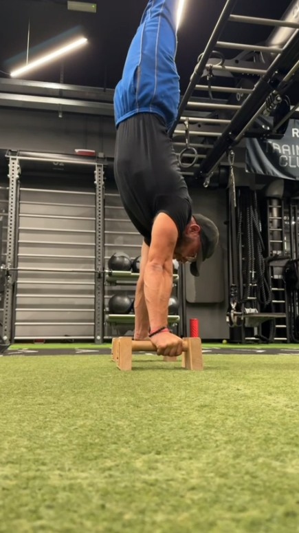 Giacomo in verticale sulle parallettes in palestra